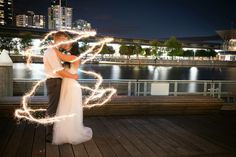 a bride and groom pose with sparklers in their hands on the boardwalk at night