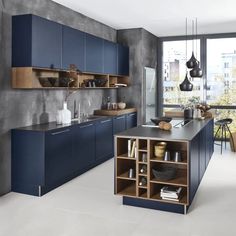 a modern kitchen with blue cabinets and counter tops in front of a large window overlooking the city