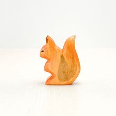 an orange squirrel figurine sitting on top of a white table