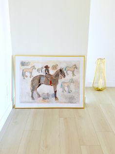 a painting is on the floor next to a vase with flowers and a horse in it