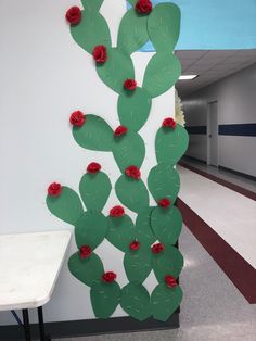 a paper cactus with red flowers on it next to a white wall in an office