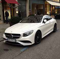 a white car is parked on the side of the road in front of a building