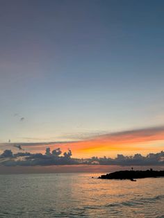 the sun is setting over an island in the ocean