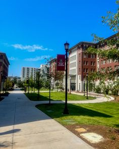 an empty sidewalk in front of a building with trees and grass on the side walk