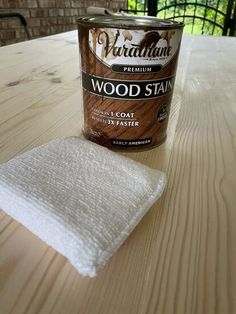 a can of wood stain sitting on top of a wooden table next to a white towel