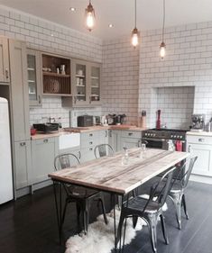 a kitchen with a table and chairs in the center, lights hanging from the ceiling