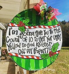 a green and white christmas ornament hanging from the side of a wooden fence