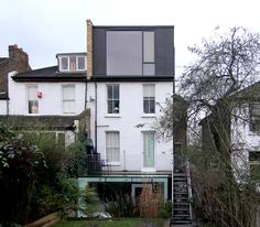 the house is white with black trim and has stairs leading up to it's second floor