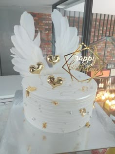 there is a white cake with gold decorations on the top and wings in the middle