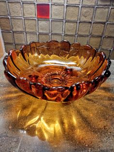 a brown glass bowl sitting on top of a counter next to a tile backsplash