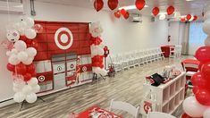 an empty room with red and white balloons on the ceiling, tables and chairs set up for a party