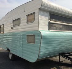 an old blue and white trailer parked in a parking lot