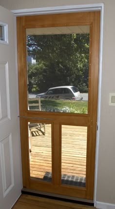 an open door with a car parked in the yard through it's glass pane