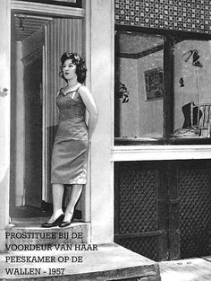 an old black and white photo of a woman standing in front of a door with her hands on her hips