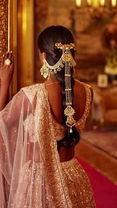 the back of a woman's head wearing a gold and white sari with jewels on