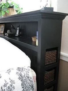 a bed with a black headboard and some baskets on the bottom shelf next to it