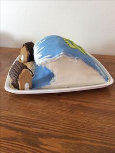 there is a cake shaped like a house on top of a plate with cookies in the shape of a mountain