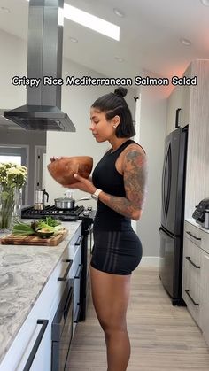 a woman standing in a kitchen holding a large piece of meat on top of a counter