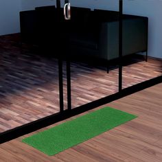 a living room with wooden floors and green rugs on the floor next to a black couch