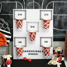 an orange and black basketball themed party with popcorn buckets on the table next to it