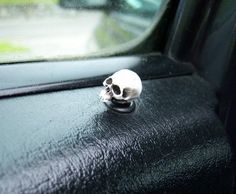 a small white skull sitting on the side of a black car door window sill