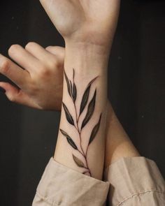 a woman's wrist tattoo with leaves on it