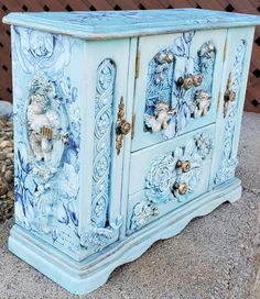 an ornate painted blue cabinet sitting on top of a sidewalk