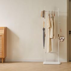 a coat rack with umbrellas and clothes hanging on it next to a wooden cabinet