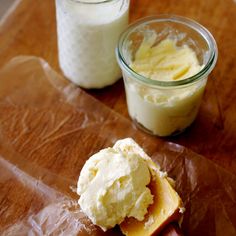 a wooden table topped with two jars of cream and a hot dog on top of wax paper