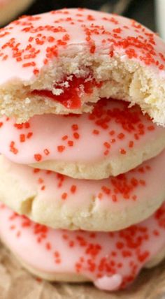 three cookies with pink icing and red sprinkles are stacked on top of each other