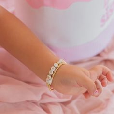 a child's hand wearing a bracelet with pearls