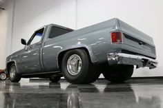 a gray pick up truck parked in a garage next to a white wall and black floor