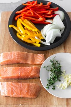 salmon, peppers, and onions on a cutting board next to a bowl of seasoning