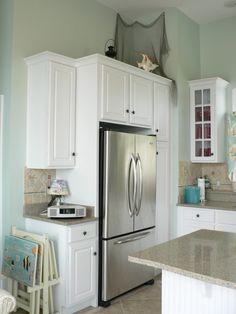 a stainless steel refrigerator freezer sitting in a kitchen next to white cabinets and counter tops