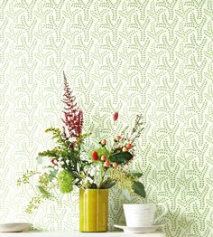 two vases filled with flowers sitting on top of a table next to a wall