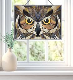 an owl stained glass window hanging in front of a white vase