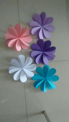 four different colored paper flowers hanging on the wall