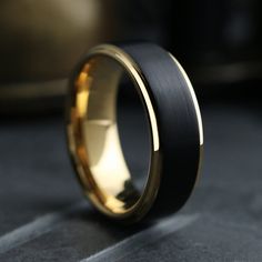 a black and gold wedding ring on top of a table