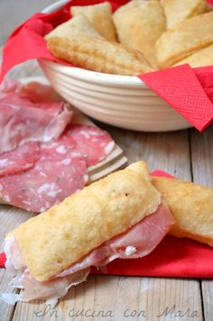 a ham and cheese sandwich cut in half on a red napkin next to a bowl of crackers