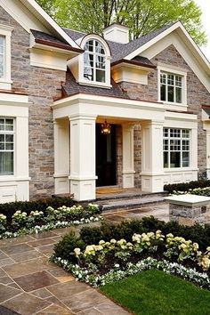 a large house with lots of windows and landscaping around the front door, along with white flowers