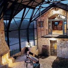 the inside of a house with an outside patio and glass walls, overlooking a river