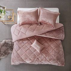 a bed with pink comforters and pillows