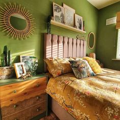 a bedroom with green walls and yellow bedding, wooden dressers and pictures on the wall