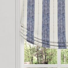 a blue and white striped roman blind in front of a window with an outside view