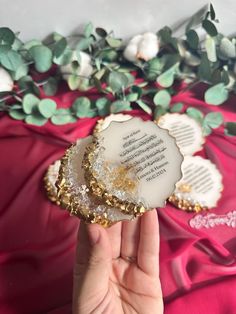 a person holding up a piece of glass with writing on it and flowers in the background