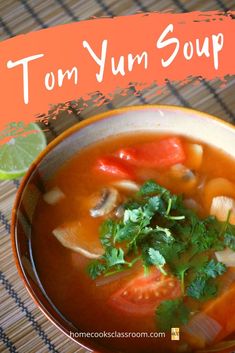 a bowl of tom yum soup with cilantro and lime on the side