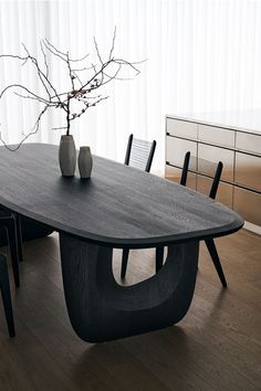 a table with two vases sitting on top of it next to a dresser and chair