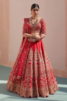 a woman in a red and gold bridal gown standing with her hands on her hips