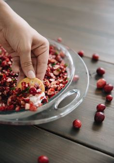 someone picking up cranberries from a glass bowl