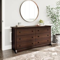 there is a large mirror on the wall above a dresser with drawers and a potted plant